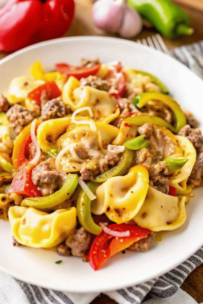 Slow cooker filled with Crock Pot Cheesesteak Tortellini with golden melted cheese and fresh vegetables.