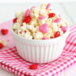 Valentine Day White Chocolate Popcorn coated in pink white chocolate with Valentine M&Ms and festive sprinkles