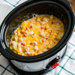 Creamy Kentucky Crockpot Potatoes topped with melted cheddar cheese and fresh parsley in a slow cooker.