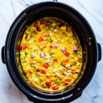 Crockpot Breakfast Casserole loaded with golden hash browns, melted cheddar, sausage, bacon, and colorful bell peppers