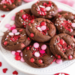 A batch of freshly baked Valentines Pudding Cookies topped with colorful Valentine M&Ms and sprinkles on a cooling rack.