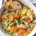 Slow Cooker Chicken Stew with tender chicken, creamy rice, and melted butter in a casserole dish