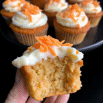 Keto carrot cake cupcakes topped with creamy cream cheese frosting on a cooling rack.