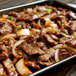 Easy Sheet Pan Beef Bulgogi with caramelized onions and snap peas served over white rice.