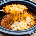 Crockpot taco casserole with melted cheese and seasoned ground beef in a slow cooker.