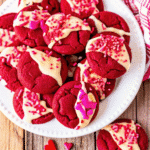 Valentine Day Red Velvet Cookies dipped in white chocolate and topped with festive Valentine sprinkles on a baking tray