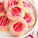 Valentine Thumbprint Cookies with pink and red chocolate centers topped with festive sprinkles on a baking tray
