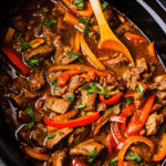 Crock Pot Pepper Steak with tender beef strips, colorful bell peppers, and onions in a rich savory sauce, ready to serve over rice.