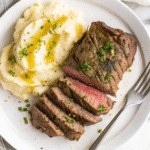Plate of creamy beef pasta with melted cheese and fresh herbs, served in a white bowl