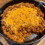 Cheesy Sloppy Joe Rice Skillet made with ground beef, tomato-based sauce, and instant rice, topped with melted cheddar cheese.