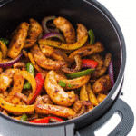 Juicy chicken strips with red, yellow, and green bell peppers and red onions cooked in an air fryer, served ready to enjoy.