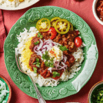 A bowl of game day ground beef chili topped with beans and spices, served over hot rice.