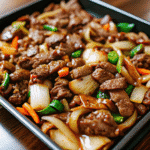 Sheet Pan Beef Bulgogi with caramelized onions and snap peas served over white rice.