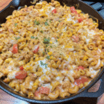 Cheesy Chicken Taco Pasta Skillet topped with fresh cilantro served in a large skillet with creamy taco-seasoned sauce and tender chicken pieces.