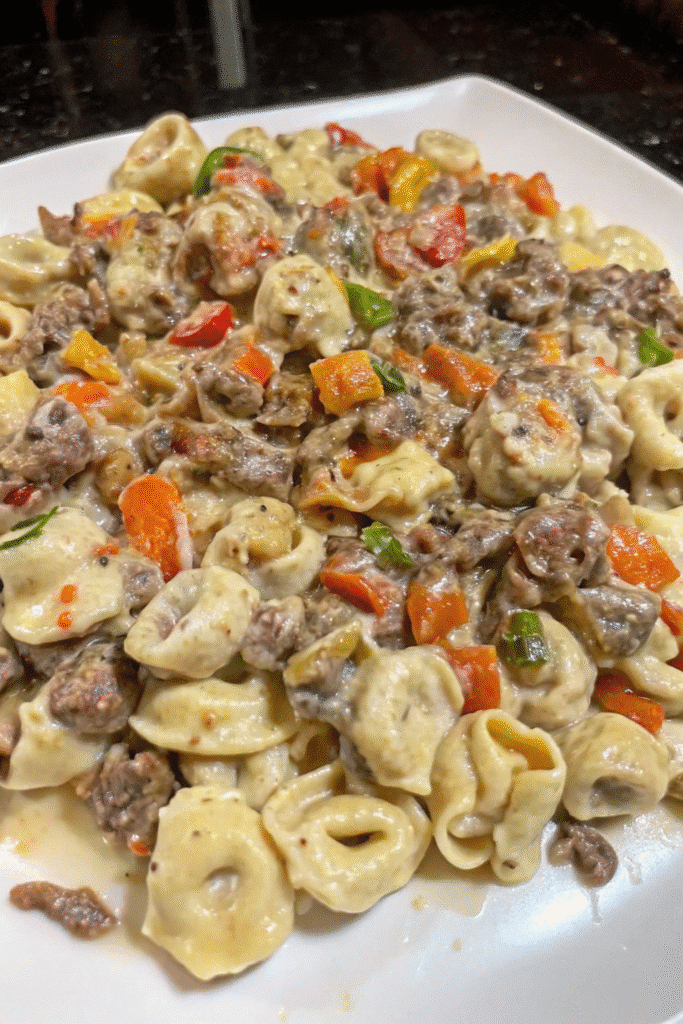 Close-up of Cheesy Philly Steak Tortellini Skillet showing creamy tortellini pasta mixed with seasoned beef, onions, and melted provolone mozzarella sauce.