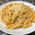 Bowl of creamy buffalo chicken penne topped with melted mozzarella and Parmesan cheese