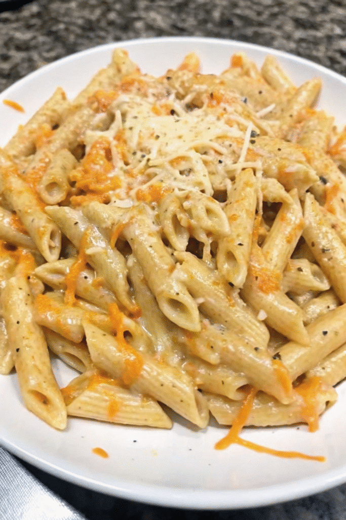 Close-up of creamy buffalo chicken penne pasta garnished with cheese and buffalo drizzle