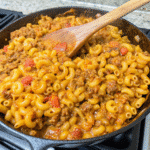 Close-up of Cheesy Chili Mac Skillet with elbow macaroni, ground beef, chili beans, tomato sauce, and melted cheddar cheese in a pan