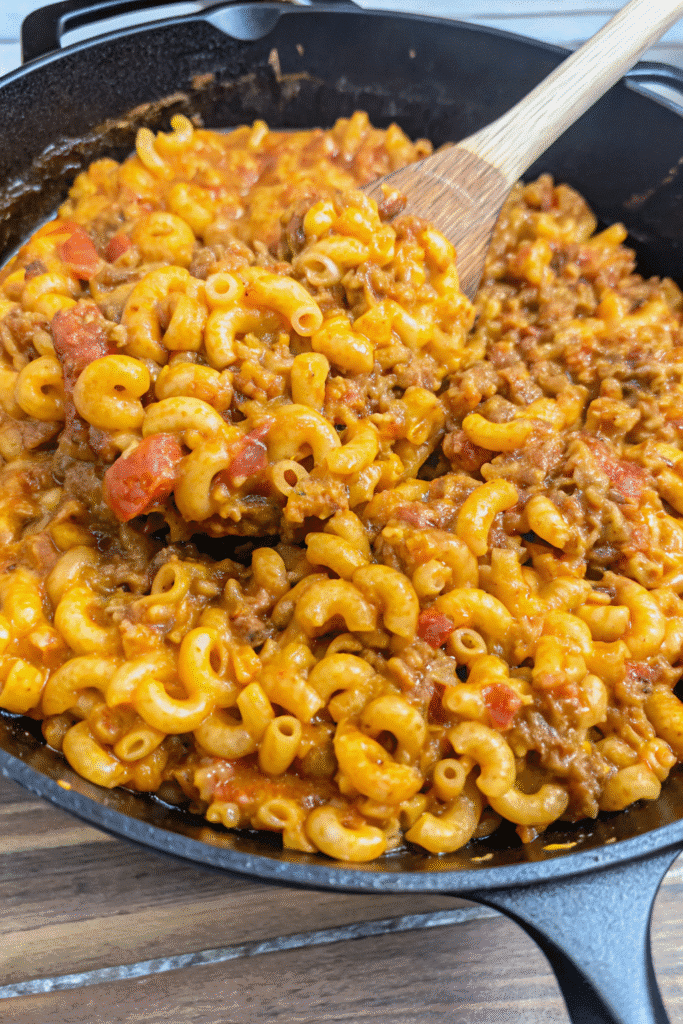 Cheesy Chili Mac Skillet Recipe 3 Serving of Cheesy Chili Mac Skillet topped with melted cheddar cheese and herbs, showing creamy pasta and beef chili mixture.