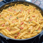 Bowl of Cheesy Queso Chicken Penne Skillet with diced chicken, creamy queso sauce, and colorful bell peppers.