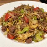Bowl of Dirty Cabbage With Smoked Turkey Sausages featuring tender cabbage, browned ground beef, and sliced smoked turkey sausage.