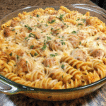 Freshly baked creamy chicken pasta bake topped with melted golden cheese and parsley in a casserole dish.