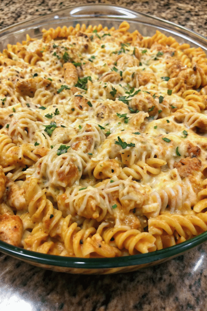 Creamy Chicken Pasta Bake Recipe 3 Close-up of creamy chicken pasta bake with rotini pasta, diced chicken, and melted mozzarella and cheddar topping.