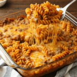 Freshly baked Cheesy Rotini Hamburger Casserole topped with melted cheddar and mozzarella cheese in a glass baking dish.