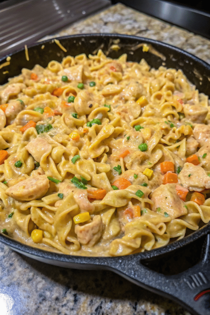 Hearty Chicken Pot Pie Pasta served in a skillet, creamy sauce coating noodles and vegetables.