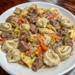 Creamy spicy steak tortellini skillet with bell peppers, jalapeños, and melted pepper jack cheese in a rustic pan.