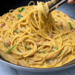 Close-up of creamy Marry Me Pasta with spaghetti coated in Parmesan and sun-dried tomato sauce, garnished with fresh basil.
