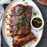 Slow-cooked St. Louis-style pork ribs coated in smoky BBQ sauce, served on a platter ready to eat.