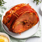 Golden brown Crockpot Spiral Ham glazed with maple syrup and brown sugar, ready to serve on a platter.