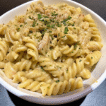 Creamy Slow Cooker Garlic Parmesan Chicken Pasta with shredded chicken and melted cheese in a white bowl.