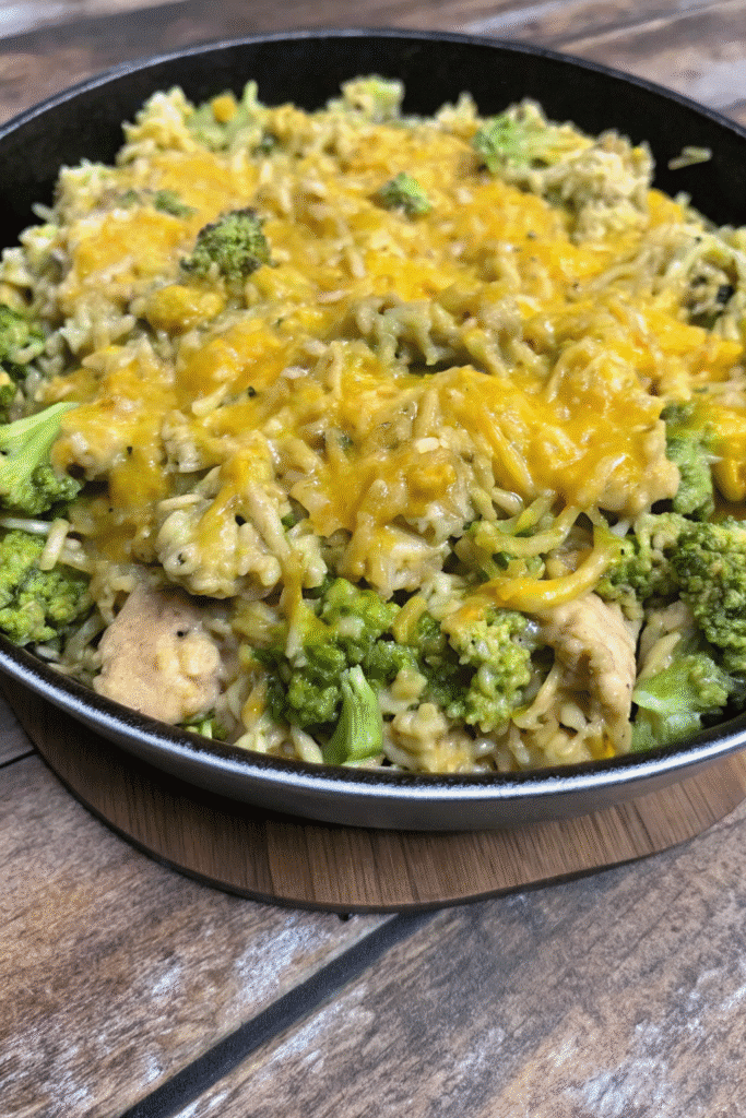 Close-up of Cheesy Chicken Broccoli Rice Skillet topped with golden melted cheddar and fresh broccoli