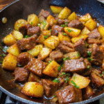 Golden crispy potatoes and seared steak cubes in a skillet garnished with fresh parsley