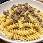 Creamy beef and rotini pasta in garlic Parmesan sauce topped with fresh parsley in a white bowl.