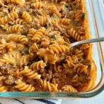 Amish Country Casserole baked with pasta, ground beef, creamy tomato and mushroom sauce, topped with melted cheddar cheese