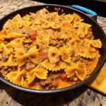 Cheesy Rotel Ground Beef Bowtie Pasta in a skillet with creamy tomato sauce, seasoned beef, and melted cheddar and mozzarella