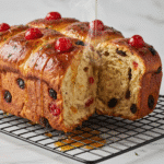 Freshly baked hot cross buns with a golden brown crust, topped with a sugar glaze, arranged in a baking dish.