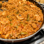 One Pot Chicken and Sausage Jambalaya with rice, chicken, sausage, bell peppers, and tomatoes in a skillet