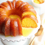 A golden Bundt Pineapple Juice Cake drizzled with sweet pineapple glaze, served on a white platter.