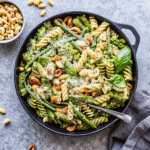 Grilled Chicken and Asparagus Pesto Pasta served in a bowl, topped with toasted pine nuts, fresh basil, and Pecorino Romano.