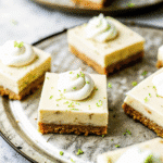 Creamy key lime pie bars with graham cracker crust topped with whipped cream and fresh lime zest.