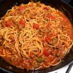 Homestyle Skillet Spaghetti with rich ground chuck tomato sauce, garlic, onions, and herbs served over tender spaghetti noodles in a large skillet.
