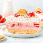 Slice of Strawberry Ice Cream Cake with layers of vanilla and strawberry ice cream, Oreo crust, and fresh strawberries on top