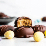 Homemade peanut butter eggs coated in smooth chocolate with a soft creamy center on a parchment-lined tray