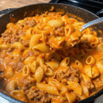 Skillet of Beefy Shells And Cheese with seasoned ground beef and creamy cheddar sauce coating tender shell pasta.