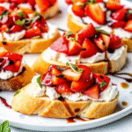 Toasted baguette slices topped with ricotta, fresh strawberries, basil, and balsamic glaze, served as Strawberry Balsamic Bruschetta appetizer.