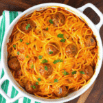 Baked Leftover Spaghetti casserole topped with melted cheddar cheese in a glass baking dish.